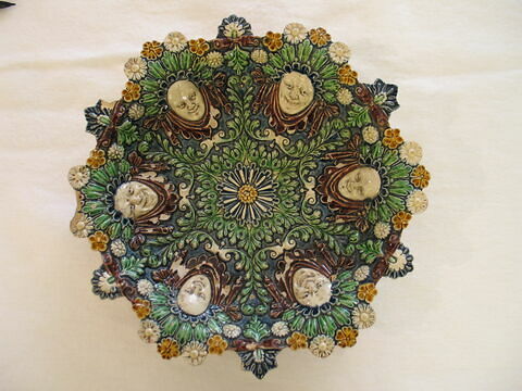 Coupe ronde, forme corbeille, à décor moulé : six mascarons et fleurs