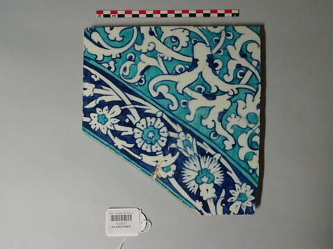 Carreau d'un tympan aux fleurons bifides rumi monumentaux sur fond turquoise. Bordures de frises d'oeillets et de feuilles dentelées sur fond bleu : arc côté droit écoinçon