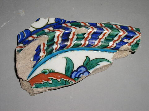 Fragment de carreau à moulure chevronnée séparant une composition florale et des entrelacs d'arabesques