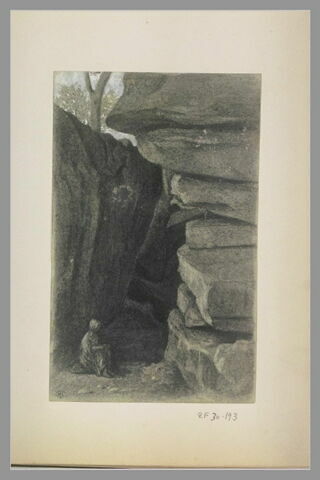 Femme assise auprès d'un bloc de roches