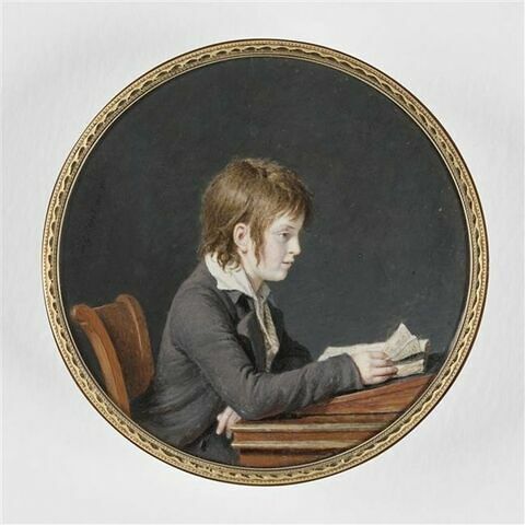 Jeune garçon, en habit gris violacé et gilet rayé, assis de profil à une table et lisant