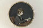 Jeune garçon, en habit gris violacé et gilet rayé, assis de profil à une table et lisant, image 2/2