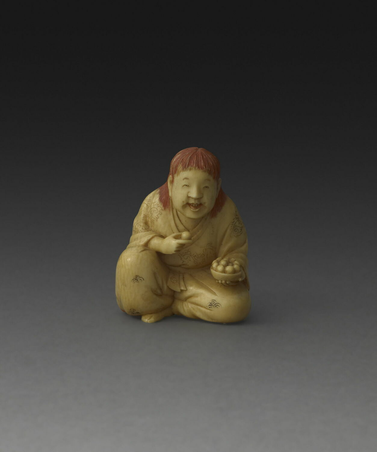 Netsuke : Homme accroupi mangeant des prunes (?)