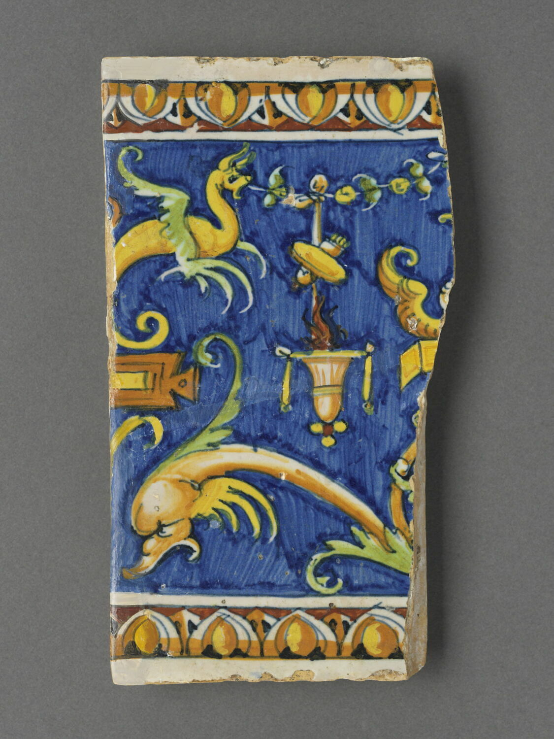 Carreau rectangulaire - pavé de bordure : décor de grotesques sur fond bleu