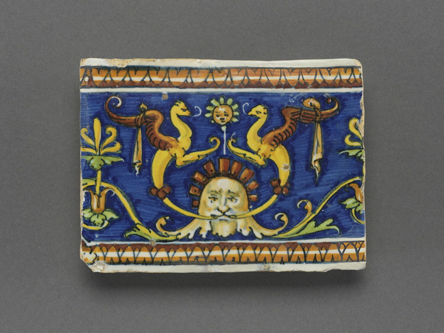 Carreau rectangulaire - pavé de bordure : décor de grotesques sur fond bleu