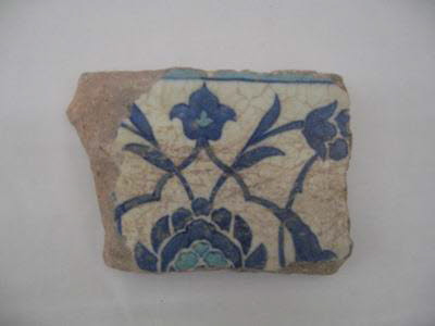 Fragment de carreau à composition symétrique de rumis, lotus, rosettes et feuilles dentelées