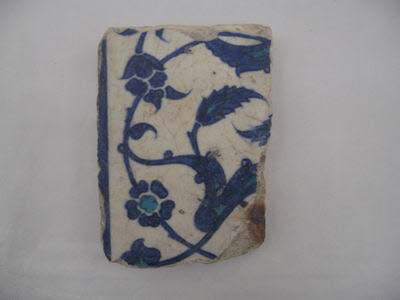 Fragment de carreau à composition symétrique de rumis, lotus, rosettes et feuilles dentelées