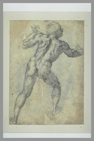 Homme debout, de dos, tenant un baton, image 2/2