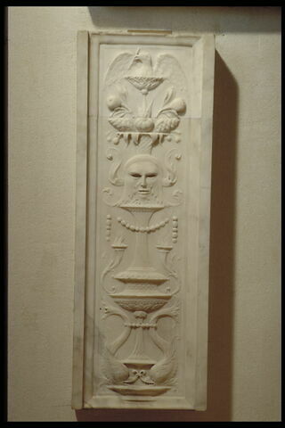Pilastre symétrique à décor de candélabre. Deux dauphins affrontés, de part et d'autre d'un vase dont sortent un masque feuillu, une corbeille de fruits et un aigle (?)