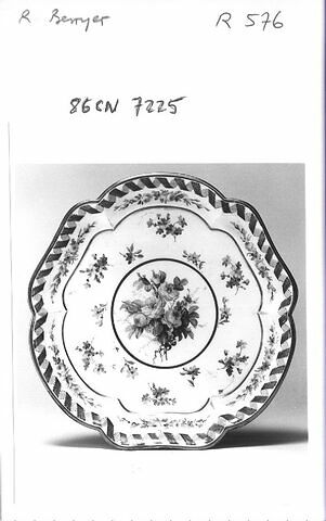 Plateau à bords contourné à six lobes, d'une série de quatre (R 576 à 579), d'un service de table (R 550 à 675) en porcelaine tendre décoré de fleurettes rehaussées de filets d'or et d'un ruban bleu sur le marli.
Sèvres XIXème siècle.
H. 0.035 L. 0.21