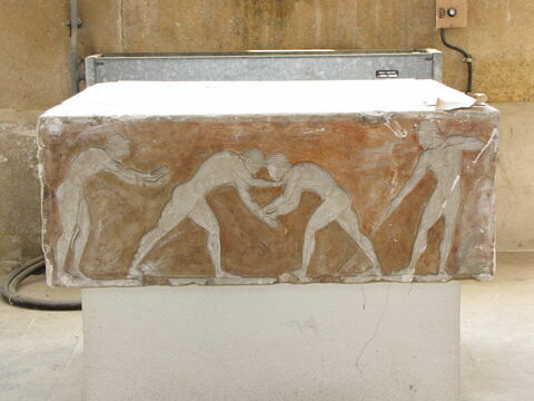 Tirage de la base d'un kouros funéraire attique
Les trois faces sont ornées de reliefs représentant deux lutteurs s'exerçant entre un coureur prêt au départ et un lanceur de javelot, deux éphèbes assis et deux autres debout regardant un chien et un chat affrontés, et six éphèbes jouant à la balle., image 3/4