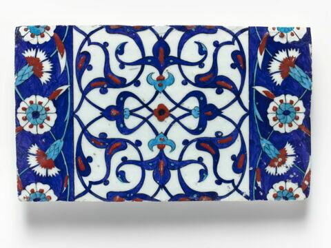 Carreau de bordure aux quadrilobes faits de fleurons bifides rumi et frises de rosettes et d'oeillets sur fond bleu, image 1/1