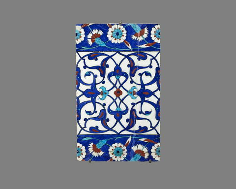 Carreau de bordure aux quadrilobes faits de fleurons bifides rumi et frises de rosettes et d'oeillets sur fond bleu