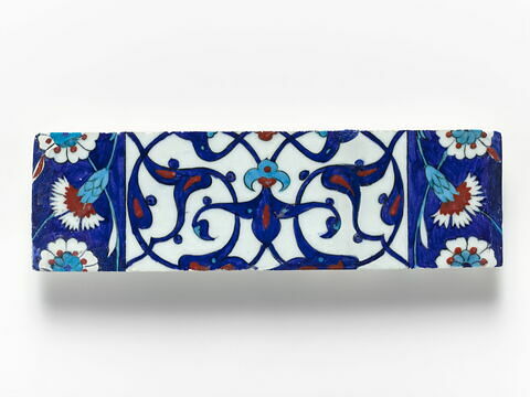 Carreau de bordure aux quadrilobes faits de fleurons bifides rumi et frises de rosettes et d'oeillets sur fond bleu, image 1/1