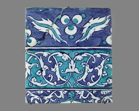 Carreau à double bordure à fleurons bifides rumi sur fond turquoise et à décor de cintemani sur fond bleu