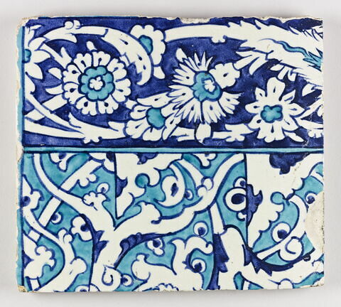 Carreau d'un tympan aux fleurons bifides rumi monumentaux sur fond turquoise. Bordures de frises d'oeillets et de feuilles dentelées sur fond bleu : carreau haut gauche, image 1/1