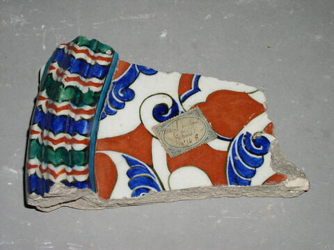 Fragment de carreau à moulure chevronnée séparant une composition florale et des entrelacs d'arabesque