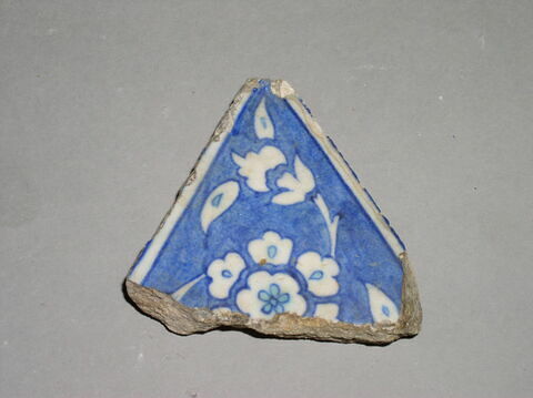 Carreau triangulaire lacunaire à la rosette en réserve sur fond cobalt