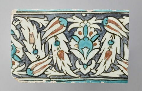 Carreau de bordure à décor de palmette, tulipes et feuilles dentelées fleuries sur fond noir