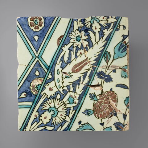 Carreau à la bande diagonale décorée d'un rinceau d'oeillets, de tulipes et de feuilles dentelées