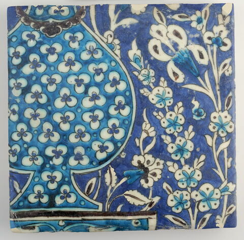 Carreau au vase à décor de cintemani et au jardin avec des iris sur fond bleu sombre
