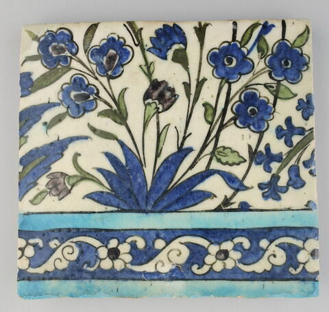 Carreau de bordure (registre inférieur) d'une composition florale, bordée d'une frise de fleurettes et de palmettes sur fond bleu cobalt