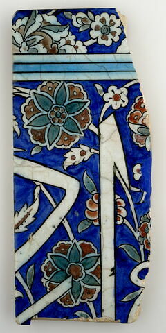 Fragment de carreau de bordure à l'inscription sur fond bleu et rinceaux à rosettes et fleurettes, image 1/2