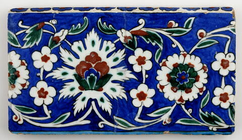 Carreau de bordure aux lotus alternant avec des fleurettes et des rosettes sur fond bleu