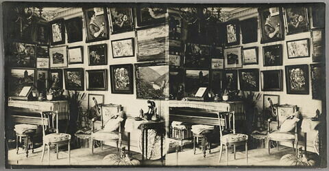 Coin d'un salon avec piano et quantité de peintures accrochées aux murs