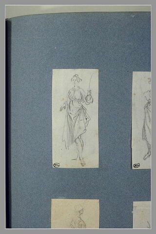 Une femme, debout, une verge dans la main gauche, image 2/2