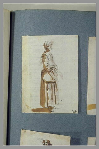Une femme, debout, tounée vers la droite, les mains devant elle, image 2/2