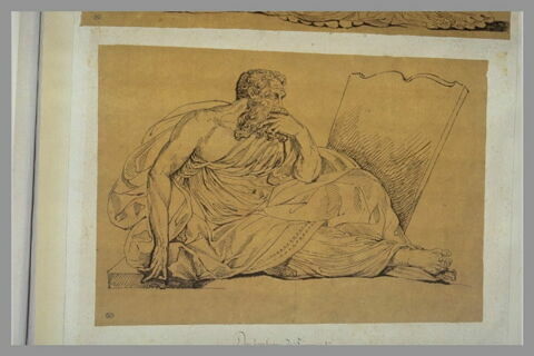 Homme assis, de profil, devant une stèle, image 1/1