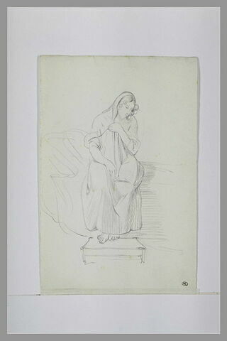 Femme assise sur un divan, de face, retenant de la main gauche sa chemise, image 1/1