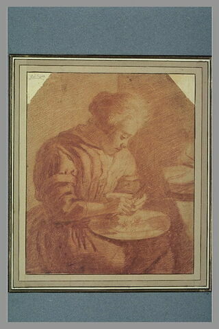 Une femme assise, coupant du pain