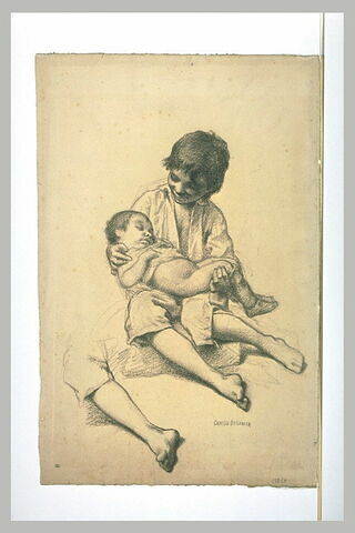 Jeune garçon assis sur le sol, de face tenant dans ses bras un enfant