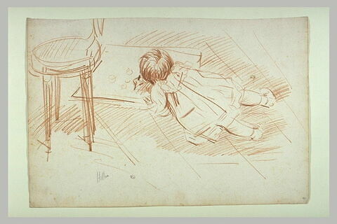 Paulette enfant, à plat ventre par terre, dessinant