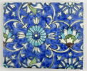 Carreau au quadrilobe accompagné de fleurs épanouies saz et de rosettes sur fond bleu, image 1/3